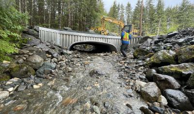 A worker walks in front of a recently replaced culvert in Alaska.