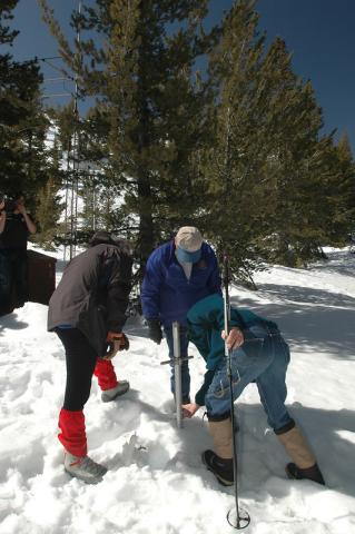 Three people are taking a core from snowpack in Nevada