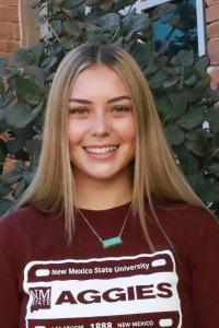 Picture of a young woman with long blond hair, wearing an NMSU aggies sweatshirt 