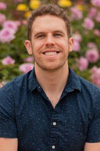 A man sits in front of flowers.