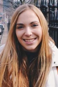 Woman with long hair standing in a city street, smiling at the camera