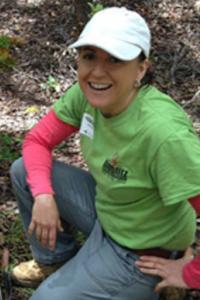 Amy Koch kneeling wearing white hat and green T-shirt