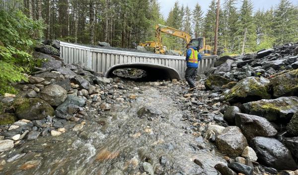 A worker walks in front of a recently replaced culvert in Alaska.